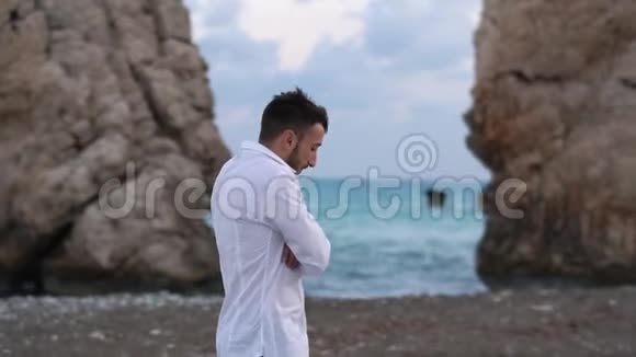 年轻英俊的男子走在多风的海边在岩石之间的海滩上塞浦路斯帕福斯视频的预览图