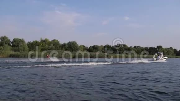 极限水上运动人在摩托艇后的尾板上冲浪在大自然的背景下水沿着河流飞溅视频的预览图