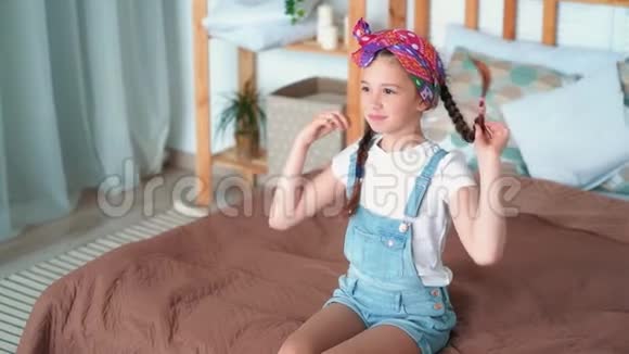 可爱的女孩玩辫子坐在床上姐姐跳在她身上慢动作视频的预览图