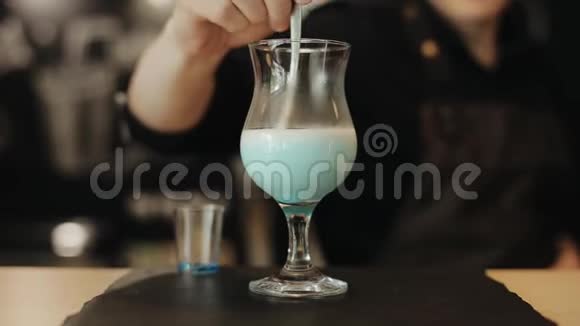 咖啡师用勺子把牛奶倒在酒杯里特写镜头视频的预览图