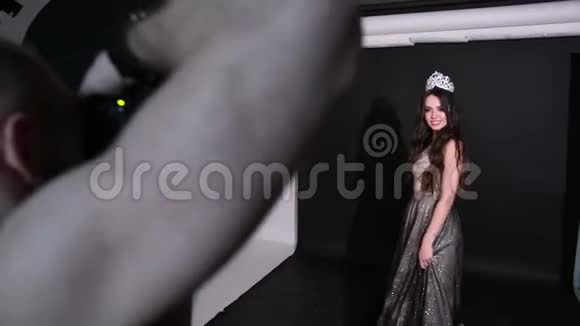 摄影师照片模特深色头发穿着闪亮的裙子在摄影棚里视频的预览图