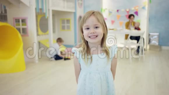 漂亮的小女孩站在镜头前而其他孩子则在背景上玩耍视频的预览图