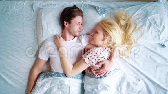 早上面对面躺在床上的幸福夫妇的俯视图放大视频的预览图