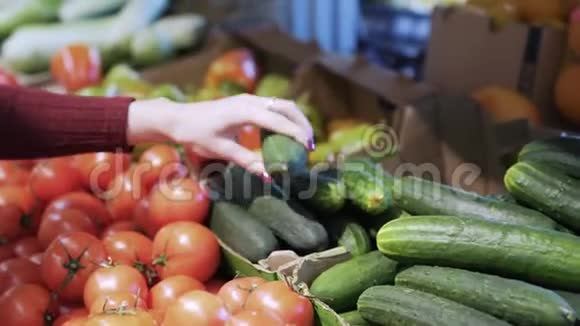特写女人的手把黄瓜从柜台放在塑料袋里放蔬菜视频的预览图