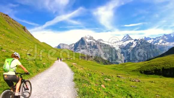 格林德尔瓦尔德骑在瑞士阿尔卑斯山的女山地自行车手著名的山脉丛林艾格和蒙奇的背景视频的预览图