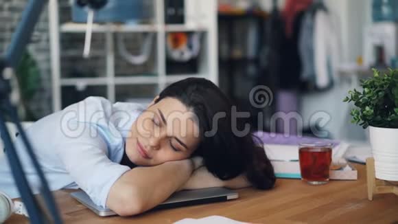 劳累了一天的年轻妇女在工作中躺在笔记本电脑上休息视频的预览图