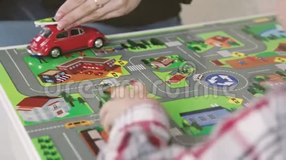 微笑的女人儿童心理学家和男孩在孩子们桌子上玩五颜六色的汽车视频的预览图