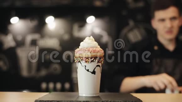 一位男咖啡师用手在奶昔上撒甜甜圈和鲜奶油视频的预览图