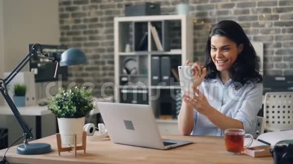 情绪化的年轻女性在办公室用智能手机进行在线视频通话视频的预览图