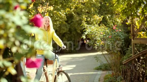 穿着针织毛衣的金发美女正在公园骑自行车春天的浪漫少女视频的预览图