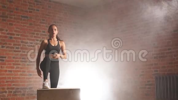 漂亮的女性健美运动员在健身房里跳在合适的盒子上视频的预览图