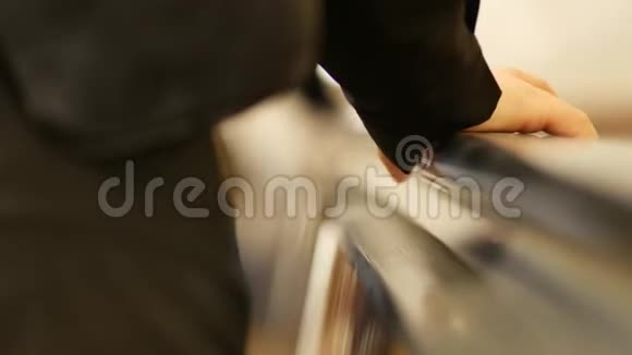 在自动扶梯上的乘客手举的特写妇女身体部分视频的预览图