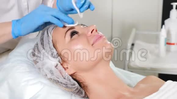 美容准备美容师在美容前用棉垫清洁女性皮肤手套美容师视频的预览图