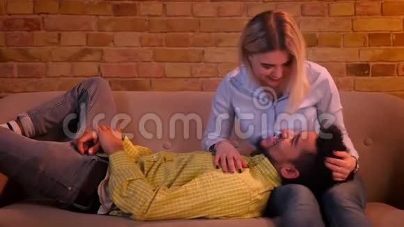 近距离拍摄的非洲男人躺在白种人女朋友的腿上在家里的气氛中抚摸他视频的预览图