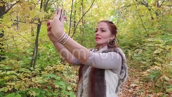 美丽的生活方式女人鲜艳的妆容在秋天的公园里自拍视频的预览图