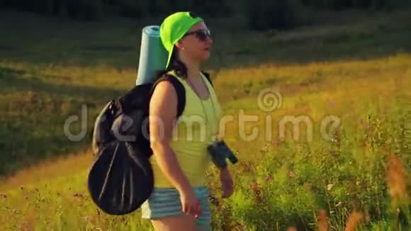 女徒步旅行者肩上背着背包用双筒望远镜登山视频的预览图