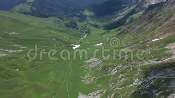 夏天在阿代盖山的一个山谷上空向后飞行绿树和灌木丛中的岩石和雪视频的预览图