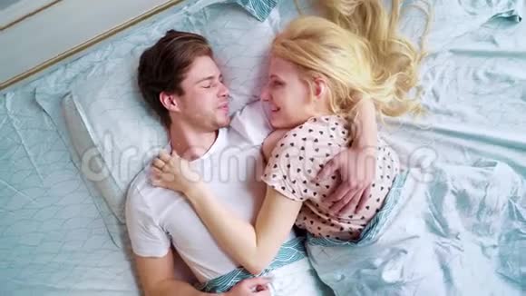 镜头在爱的一对情侣的上空盘旋在清晨面对面地躺在床上视频的预览图