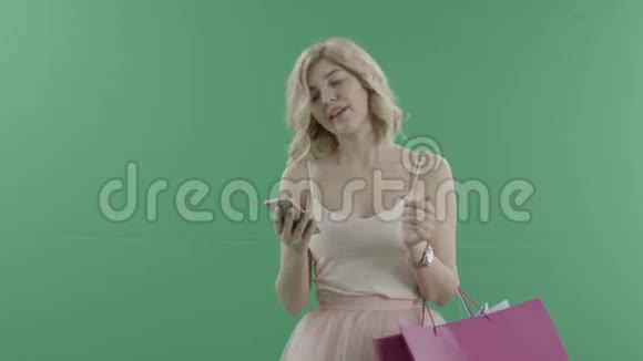 年轻女子拿着袋子在智能手机上用绿色屏幕打电话视频的预览图