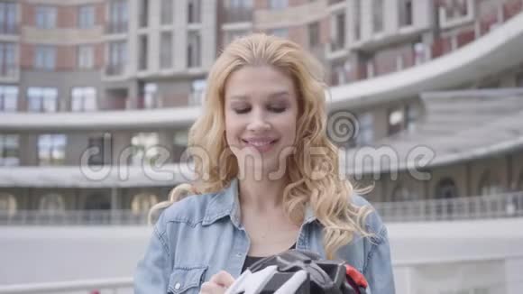 肖像可爱的金发女人头上戴着自行车头盔在城市的背景下骑着自行车视频的预览图
