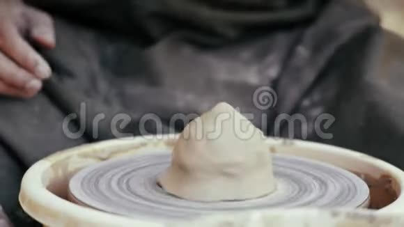 特写镜头穿着围裙的陶工在陶圈的基础上展开视频的预览图