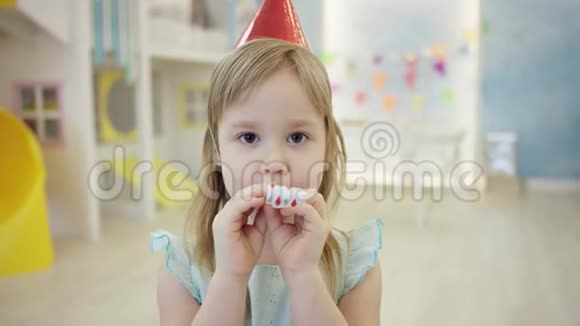 近距离拍摄了一个戴着锥帽的小女孩站在游戏室镜头前吹口哨视频的预览图
