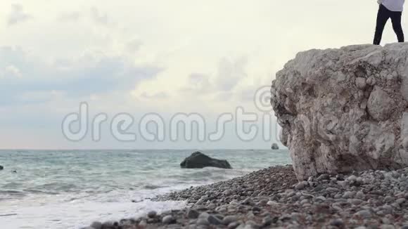 男人坐在高高的岩石山上欣赏着令人惊叹的海滨景色容曼欣赏大海的景色视频的预览图