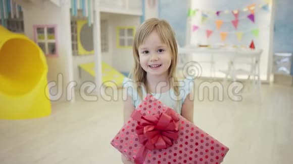 可爱的小女孩站在一个房间里手里拿着大礼盒在镜头前视频的预览图