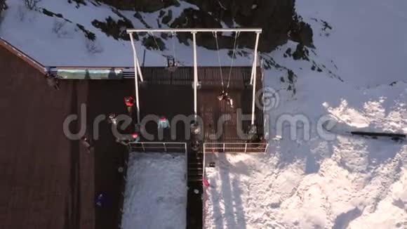 鸟瞰人们在冬季山景的悬崖边摇摆游客在滑雪场的冬季秋千上摇摆视频的预览图