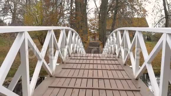 多云的秋日摄像机沿着一座白色的桥慢慢移动在树周围视频的预览图