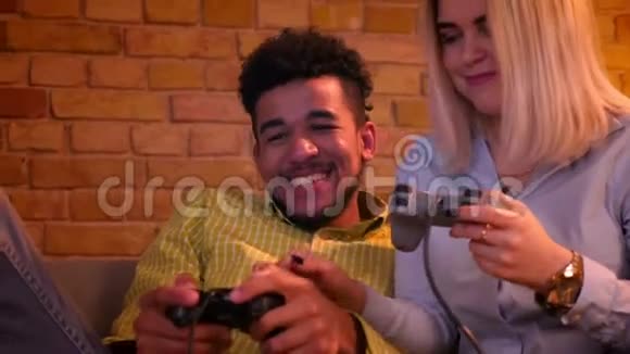 非洲男人和他的金发白种人女朋友玩电子游戏在家里给对方五个视频的预览图