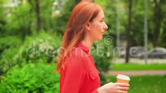 红头发女商人喝卡布奇诺走在户外视频的预览图