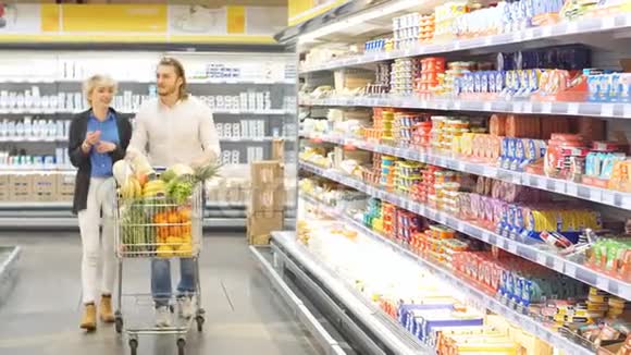 积极的家庭顾客在杂货店里装满健康的有机蔬菜和水果视频的预览图