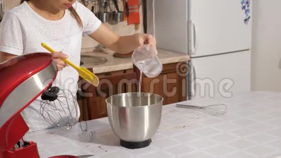 女人正在搅拌机碗里倒糖浆来煮奶油做蛋糕视频的预览图