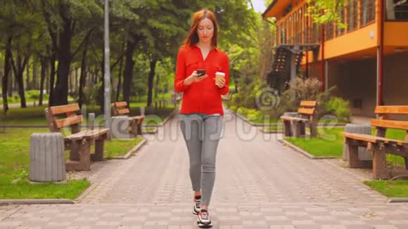 留着红色长发的女人在城市里用手握杯子散步视频的预览图