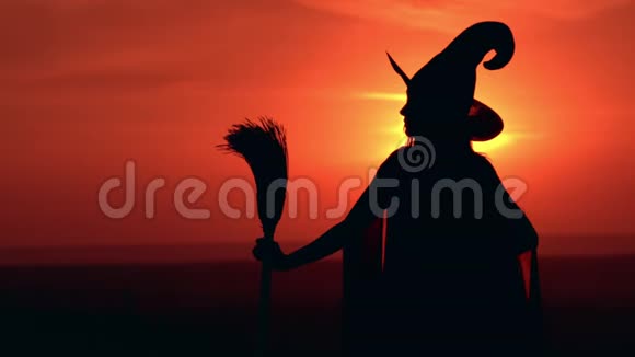 穿着花式服装的侧视女孩女巫拿着扫帚看日出视频的预览图