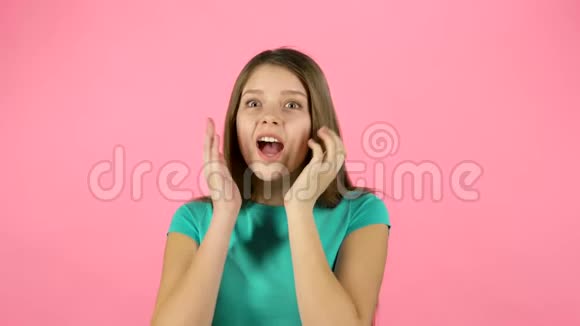 小女人很惊讶在粉红色的背景上拍手视频的预览图