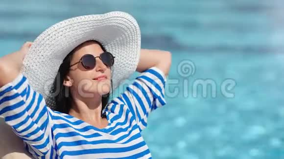 放松微笑时尚女性在游泳池附近享受日光浴享受暑假视频的预览图