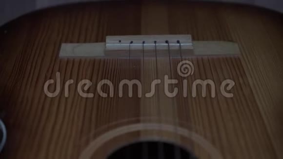 金属琴弦在昂贵的木制吉他上伸展视频的预览图