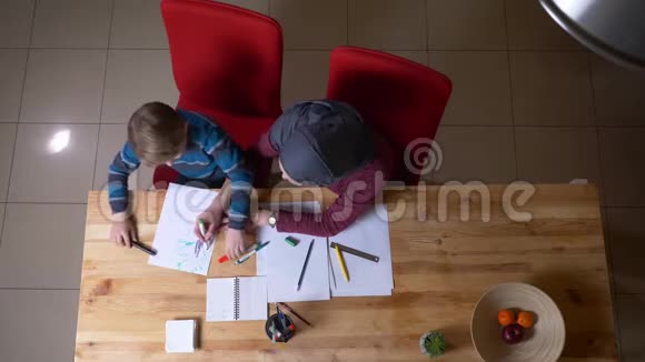 穆斯林母亲戴头巾帮她儿子用桌子上的标记画这幅画视频的预览图