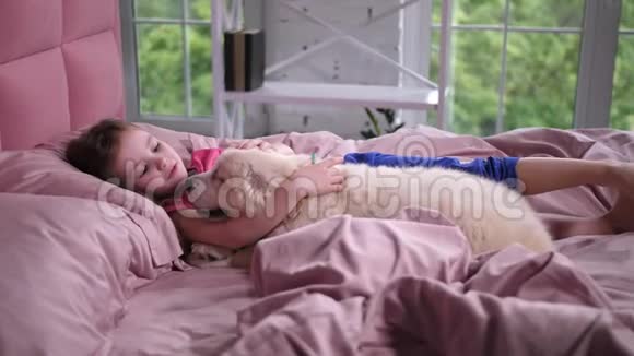 可爱的小女孩和躺在床上的小狗说话视频的预览图
