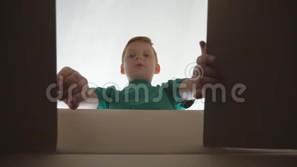 小男孩看着盒子脸上有情感和感情带礼物的儿童开箱拉着手拿视频的预览图