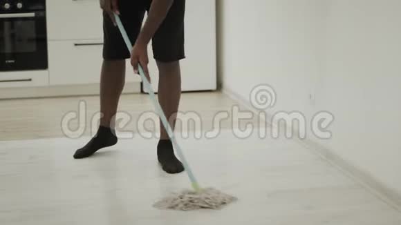 黑人用拖把清洁厨房的地板严肃的家伙洗袜子地板视频的预览图