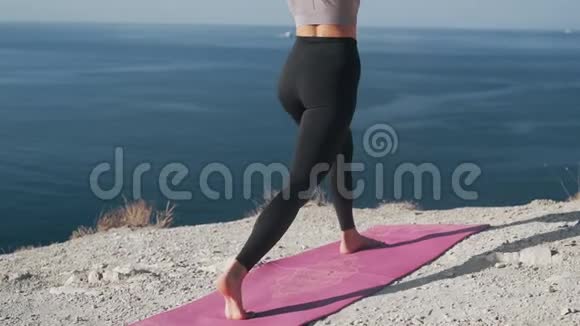 在户外女人蹲在垫子里训练她的身体海景视频的预览图