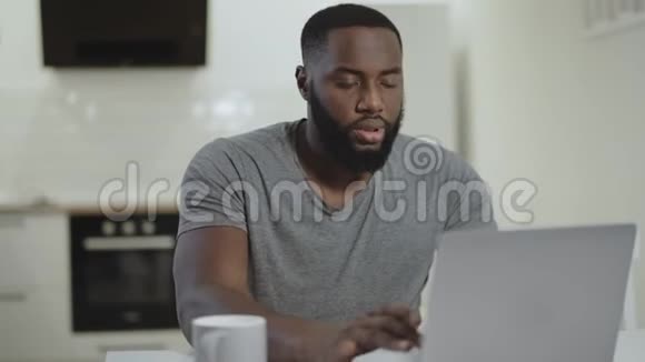 可怜的黑人在开放式厨房工作笔记本电脑疯狂的年轻人在打笔记本视频的预览图