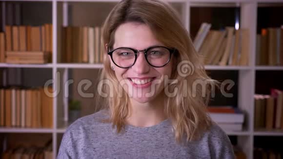 可爱的中年金发老师戴着眼镜开心地笑成镜头在图书馆里快乐视频的预览图