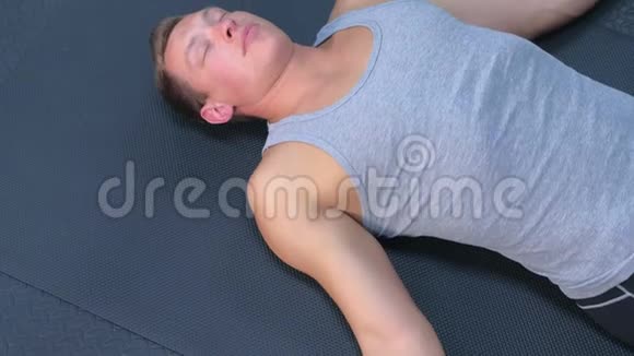运动员在健身房训练后闭着眼睛躺在垫子上休息视频的预览图