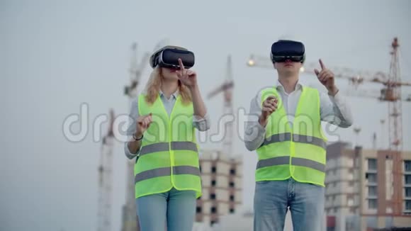两个人一男一女戴着虚拟现实眼镜在建筑背景下使用起重机视频的预览图