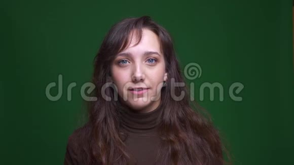 年轻的黑发女学生的肖像在绿色背景上使面部手势被激怒和困惑视频的预览图
