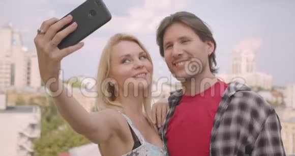一对有魅力的白种人夫妇在电话中拥抱站在房子的阳台上他们的特写照片视频的预览图